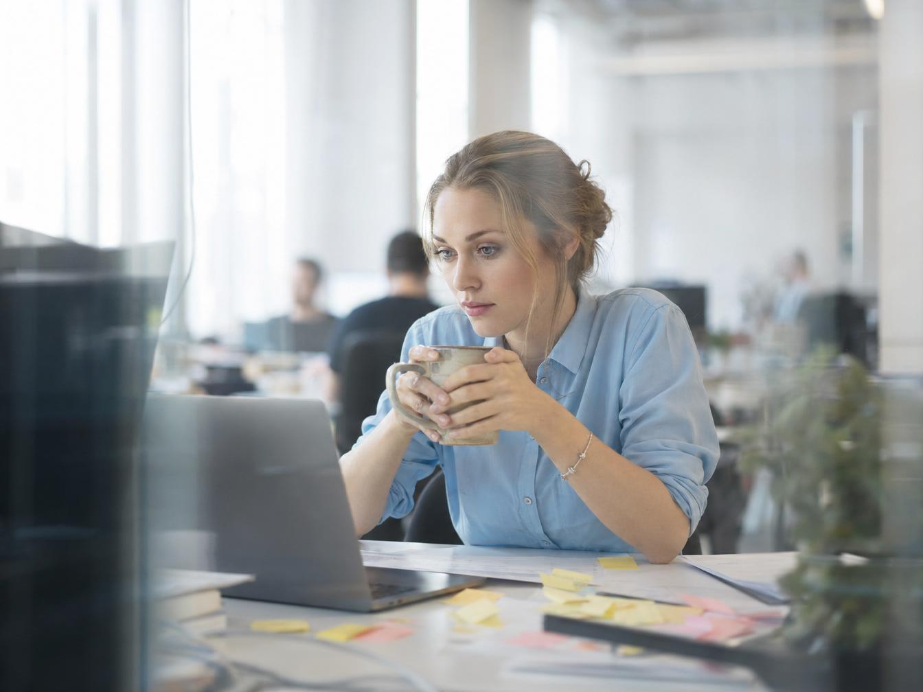 Femme travaillant sur ordinateur avec tasse de café
